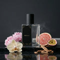 Perfume bottle labeled 'BELLA' with flowers, fruit, and cinnamon on a dark background