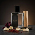 Perfume bottle with wooden cap and 'WAJDAN' branding, surrounded by flowers and leaves on a dark surface.
