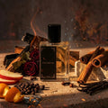 Perfume bottle labeled 'Inferno' surrounded by cinnamon sticks, oranges, and roses on a dark background.